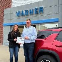 Wagner award presentation beside a red SUV